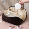 Large capacity travel makeup and cosmetic storage bag with compartments, waterproof PU leather design and portable handle for beauty essentials storage.